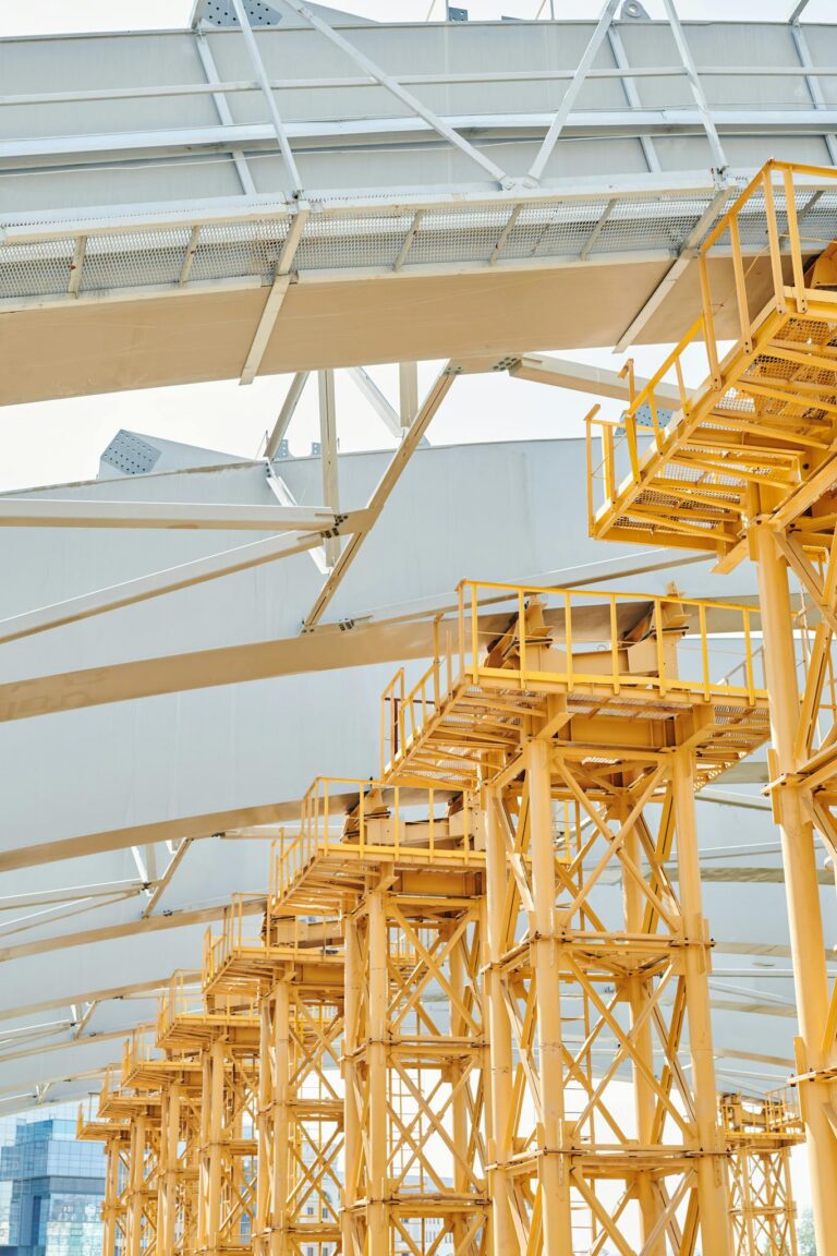 Detailed view of yellow scaffolding against a modern construction framework. Ideal for industrial themes.